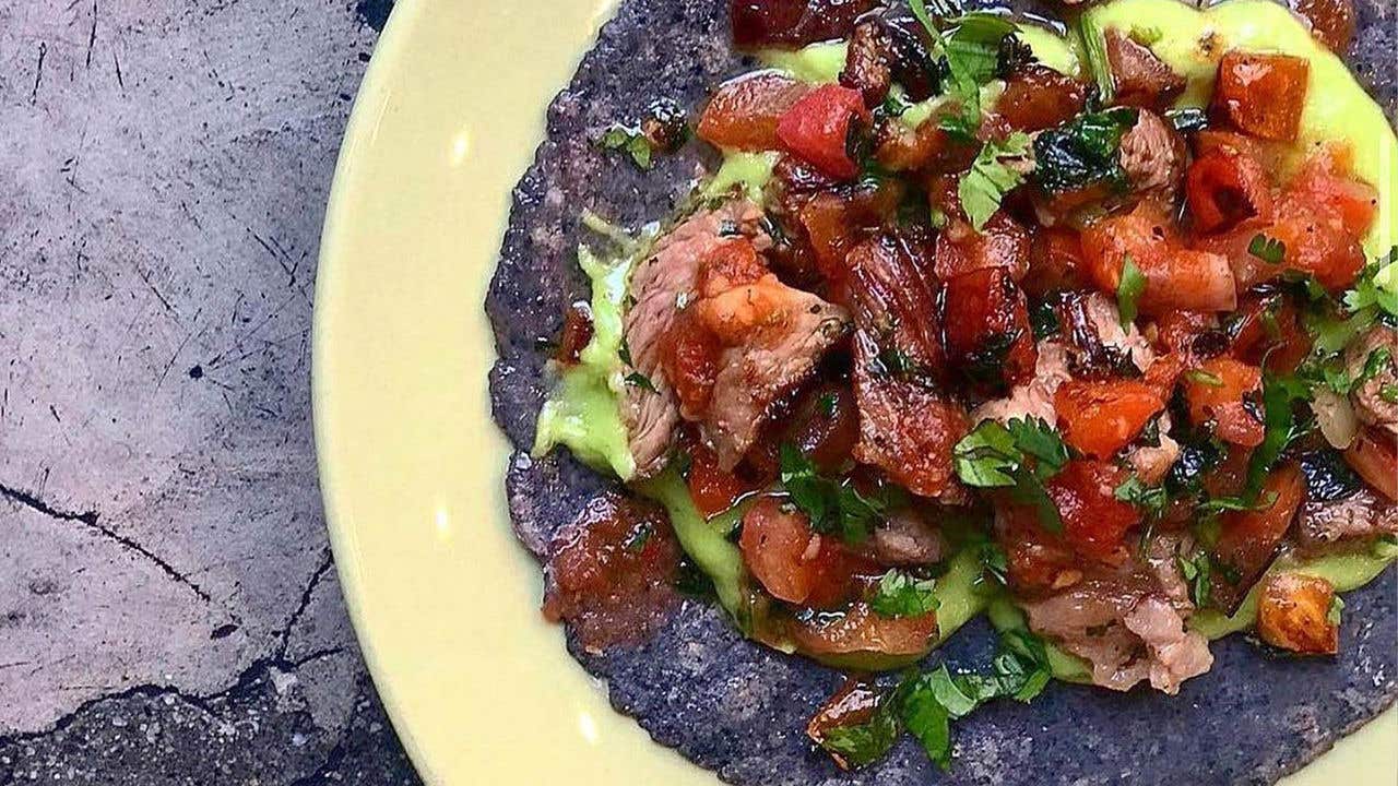 Blue corn hard taco shell with carne asada, salsa and green sauce.