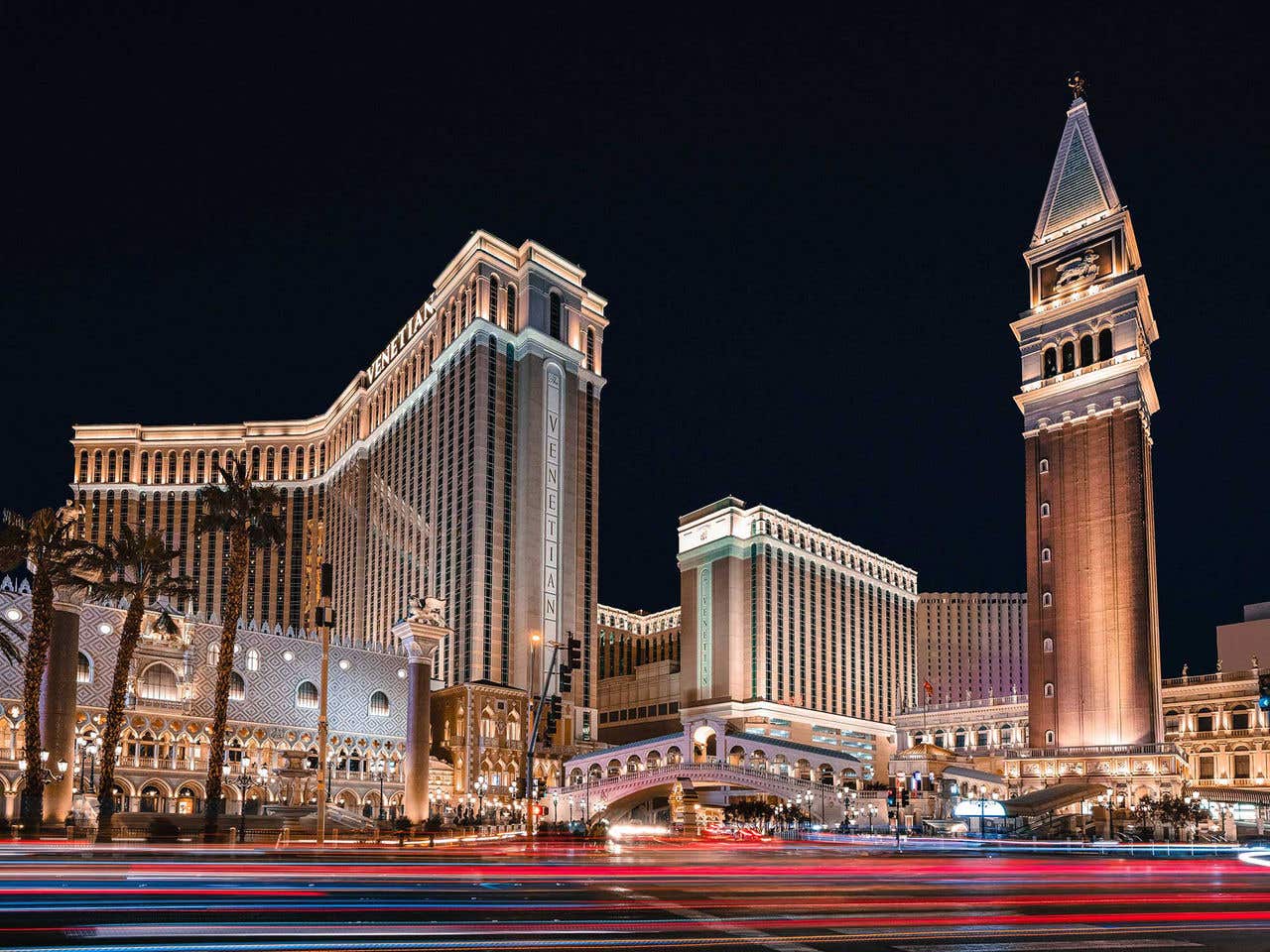 Night view of The Venetian resort in Las Vegas, showcasing its illuminated architecture and palm trees.