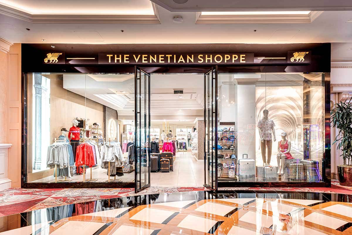 A glass storefront to a store named The Venetian Shoppe containing primarily clothing and luggage containers