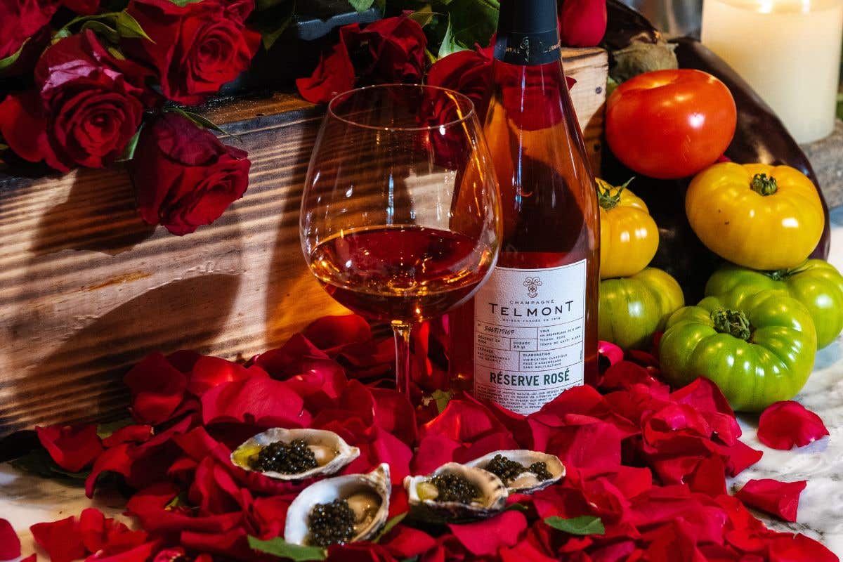 Romantic display with rosé wine, oysters, candles, and roses.
